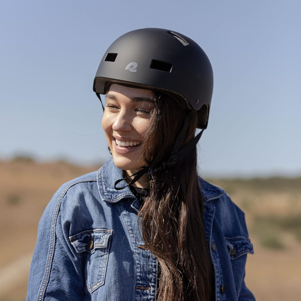 A young woman smiling outdoors while wearing a durable black protective helmet, showcasing one of the most important e scooter accessories designed for rider safety, comfort, and style during daily commutes or recreational rides.