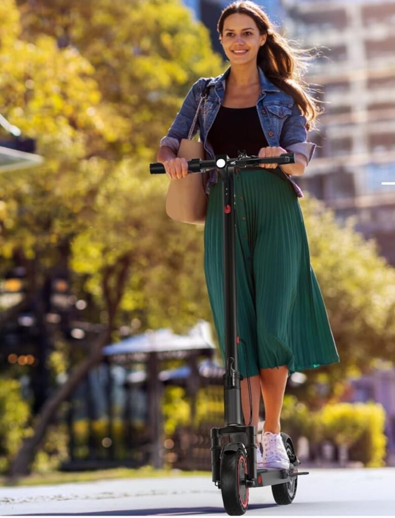 A smiling young woman rides an electric scooter through a sunny urban park, riding a sleek black scooter with red accents, possibly the MAXSHOT V1PRO Dual. The scooter is shown in motion on a smooth path. This model is featured as one of the best e scooter under $500, offering style, comfort, and value for city commuting.