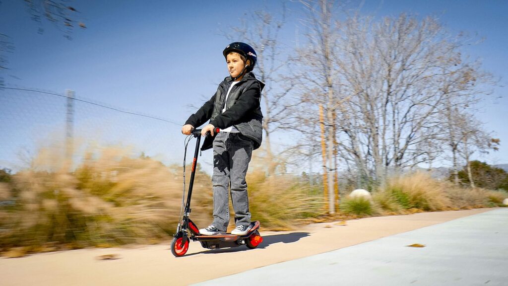 A young boy riding the Razor Power Core E90, a safe and lightweight e scooter for kids, considered among the best electric scooters for kids.