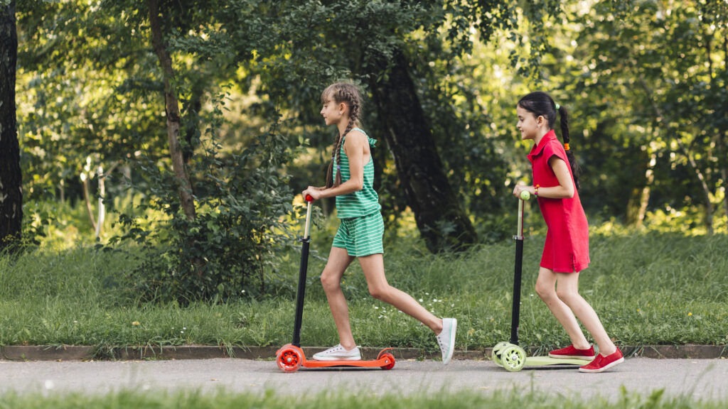 Kids riding one of the best e scooter for kids along a tree-lined path covered in golden autumn leaves, smiling and enjoying the crisp weather while showcasing the scooter’s sleek design, smooth performance, and lightweight build perfect for young riders.