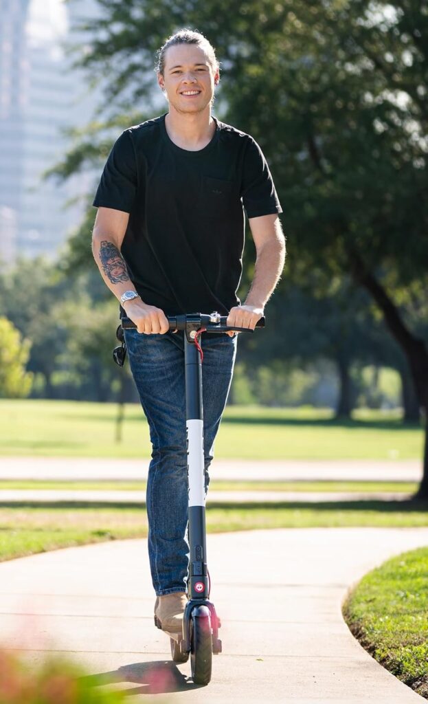 A smiling man riding an electric scooter along a park path, showcasing a stylish and comfortable ride on a popular model from the best budget e scooters category.