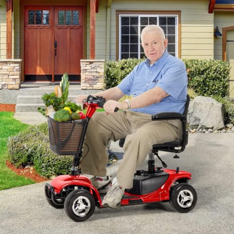An elderly man riding a red mobility scooter outside his home, carrying fresh groceries in the front basket on a paved driveway.