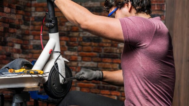 Technician repairing an electric scooter wheel in a workshop, demonstrating how to change e scooter brake pads step by step.